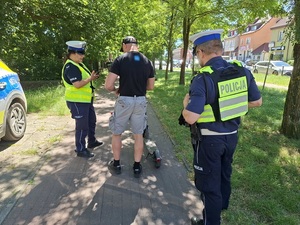 na drodze dla rowerów policjant i policjantka kontrolują mężczyznę, stojącego przy hulajnodze elektrycznej