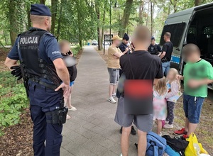 na deptaku w Łebie przy policyjnym radiowozie w towarzystwie policjantów znajduje się pięcioosobowa rodzina: matka i czworo jej dzieci.