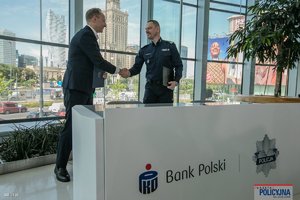w siedzibie banku PKO Komendant Główny Policji wymienia uścisk dłoni z przedstawicielem banku