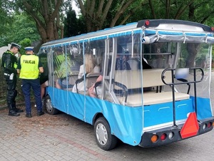 dwaj policjanci ruchu drogowego kontrolują kierowcę, który siedzi za kierownicą melexa