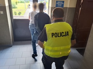 dwoje policjantów wyprowadza z budynku komendy mężczyznę skutego kajdankami
