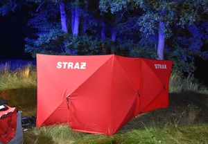 pora wieczorowa. Na trawie jest rozstawiony czerwony parawan straży pożarnej