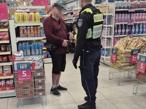 w sklepie spożywczym przed mężczyzną w kraciastej koszuli stoi policjant ruchu drogowego