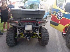 miejsce kolizji. Przed melexem stoi quad. Obok stoją kobieta i mężczyzna, po przeciwnej stronie stoi karetka pogotowia