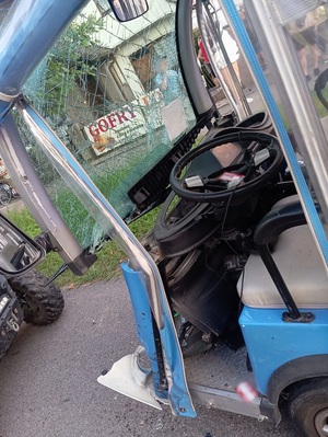 miejsce kolizji. Na jezdni stoi melex z rozbitą szybą i rozbitym przodem. Przed melexem znajduje się quad