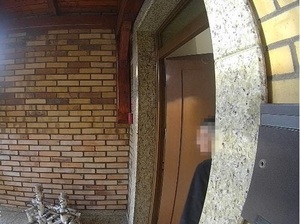 zdjęcie zrobione przez kamerę domofonu. Kobieta wychodzi z domu