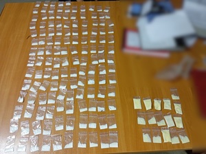 ponad 150 sztuk woreczków strunowych zawierających biały i żółty proszek, rozłożonych w rzędach na stole