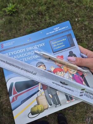 kolorowanka dla dzieci o tematyce bezpieczeństwa na obszarach kolejowych oraz długopis i opaska odblaskowa