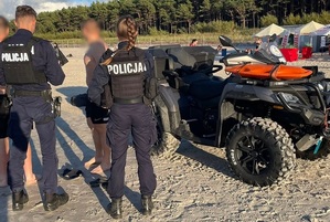 policjanci na plaży oraz wieżyczka ratowników z czerwoną flagą