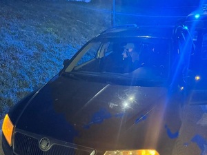 pora nocna. Na drodze stoi osobowa skoda. Na tylnym siedzeniu znajduje się dziecko