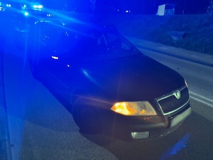 pora nocna. Na drodze stoi osobowa skoda. Za nią znajduje się policyjny radiowóz z włączonymi sygnałami błyskowymi