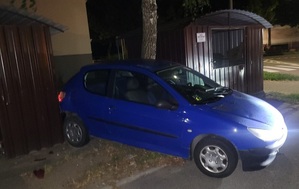 niebieski peugeot 206 stykający się tylnym zderzakiem z wiatą śmietnikową