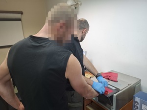 technik kryminalistyki skanuje odciski palców zatrzymanego mężczyzny