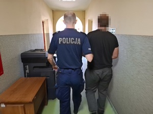 policjant prowadzi korytarzem komendy zatrzymanego mężczyznę