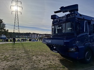 policyjny pojazd z armatką wodną zaparkowany przed stadionem. W tle policjanci ubrani w sprzęt przeciwuderzeniowy