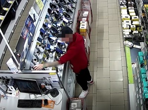 w sklepie przed regałem ze smartwatchami stoi mężczyzna, który wyciąga rękę w stronę jednego z zegarków