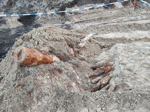 teren budowy, głębokie wykopy. Częściowo odkopane z ziemi dużych rozmiarów dwa skorodowane pociski. Obok leży pięć skorodowanych granatów moździerzowych. Teren odgrodzony taśmą policyjną