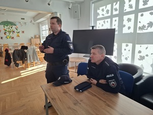 w sali klubu osiedlowego  przy stole pod oknem siedzi policjant. Drugi stoi obok i przemawia