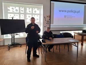 w sali klubu osiedlowego  przy stole pod oknem siedzi policjant. Drugi stoi obok i przemawia
