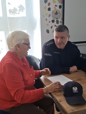 w sali klubu osiedlowego  przy stole pod oknem siedzi policjant. Obok niego siedzi starsza pani. Rozmawiają