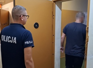 do celi wchodzi mężczyzna. Za nim stoi policjant służby dyżurnej, który przytrzymuje drzwi