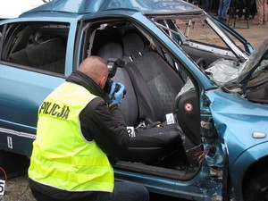 technik kryminalistyki robi aparatem fotograficznym zdjęcie wnętrza rozbitego samochodu