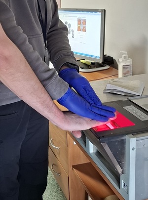 technik kryminalistyki skanuje odciski palców mężczyzny