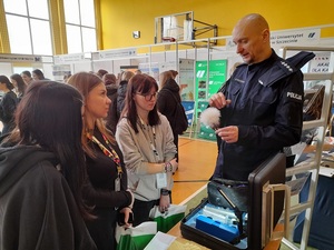 technik kryminalistyki pokazuje stojącej przed nim młodzieży pędzel używany do ujawniania śladów linii papilarnych