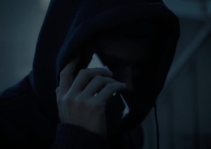 zakapturzony mężczyzna trzymający przy uchu telefon komórkowy