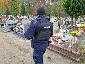 policjant służby prewencyjnej patroluje teren cmentarza