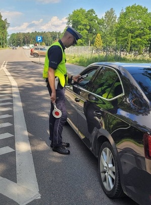 policjant ruchu drogowego kieruje alkotest w stronę kierowcy siedzącego w osobowym samochodzie