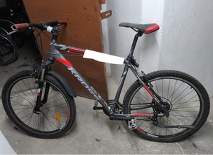 oparty o drzwi rower górski "Kross" szarego koloru, z czerwonymi zdobieniami