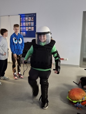 po auli lęborskiej komendy policji przechadza się chłopiec ubrany w policyjny sprzęt przeciwuderzeniowy