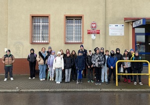zdjęcie grupowe przedstawiające uczniów i policjantkę stojących przed budynkiem Komendy Powiatowej Policji w Lęborku