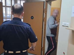 do celi wchodzi mężczyzna. W kierunku tej celi idzie policjant służby dyżurnej