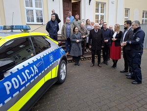 przed budynkiem lęborskiego starostwa stoi oznakowana policyjna toyota C-HR. Obok stoją przedstawiciele władz samorządowych i Komendant Powiatowy Policji w Lęborku