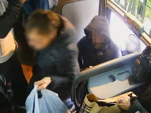 wejście do autobusu. Pierwsza idzie kobieta, za nią mężczyzna z kapturem na głowie