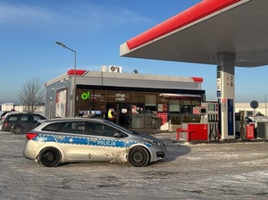 policyjny oznakowany radiowóz stojący przed stacją paliw