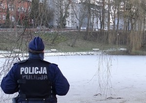 policjant stojący przed zamarzniętym stawem