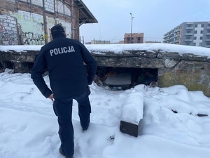 Zima. Policjant stoi przed rampą kolejową i schyla się, żeby zajrzeć do jej wnętrza.