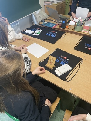 klasa szkolna. Na ławkach uczniów stoją podstawki na smartfona