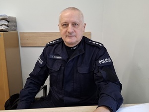 siedzący przy biurku policjant w stopniu st. aspiranta