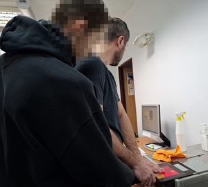 technik kryminalistyki skanuje palce zatrzymanego mężczyzny