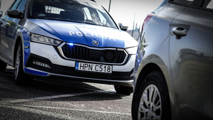 oznakowany policyjny radiowóz stojący za samochodem osobowym