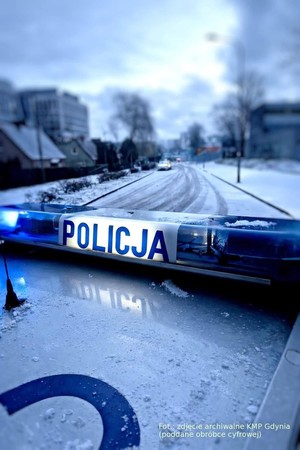 dach policyjnego oznakowanego radiowozu na ośnieżonej drodze