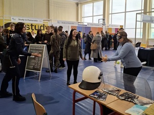 w sali sportowej przy policyjnym stoisku policjantka rzuca piłeczkę tenisową uczennicy, która ma założone narkogogle