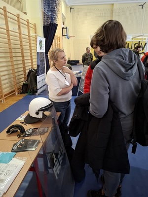 w sali sportowej przy policyjnym stoisku pracownica kadr rozmawia z uczniami