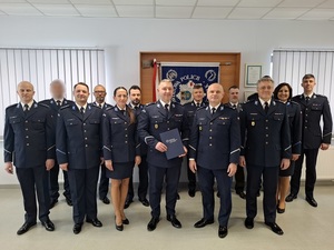 zdjęcie grupowe kadry kierowniczej lęborskiej Policji z zastępcą Komendanta Wojewódzkiego Policji w Gdańsku. Nowo mianowany p.o. Komendant Powiatowy Policji w Lęborku trzyma teczkę z rozkazem personalnym