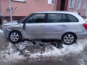 na zaśnieżonym chodniku, stykając się ze słupem stoi uszkodzona srebrna osobowa Skoda