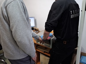 technik kryminalistyki skanuje dłoń mężczyzny